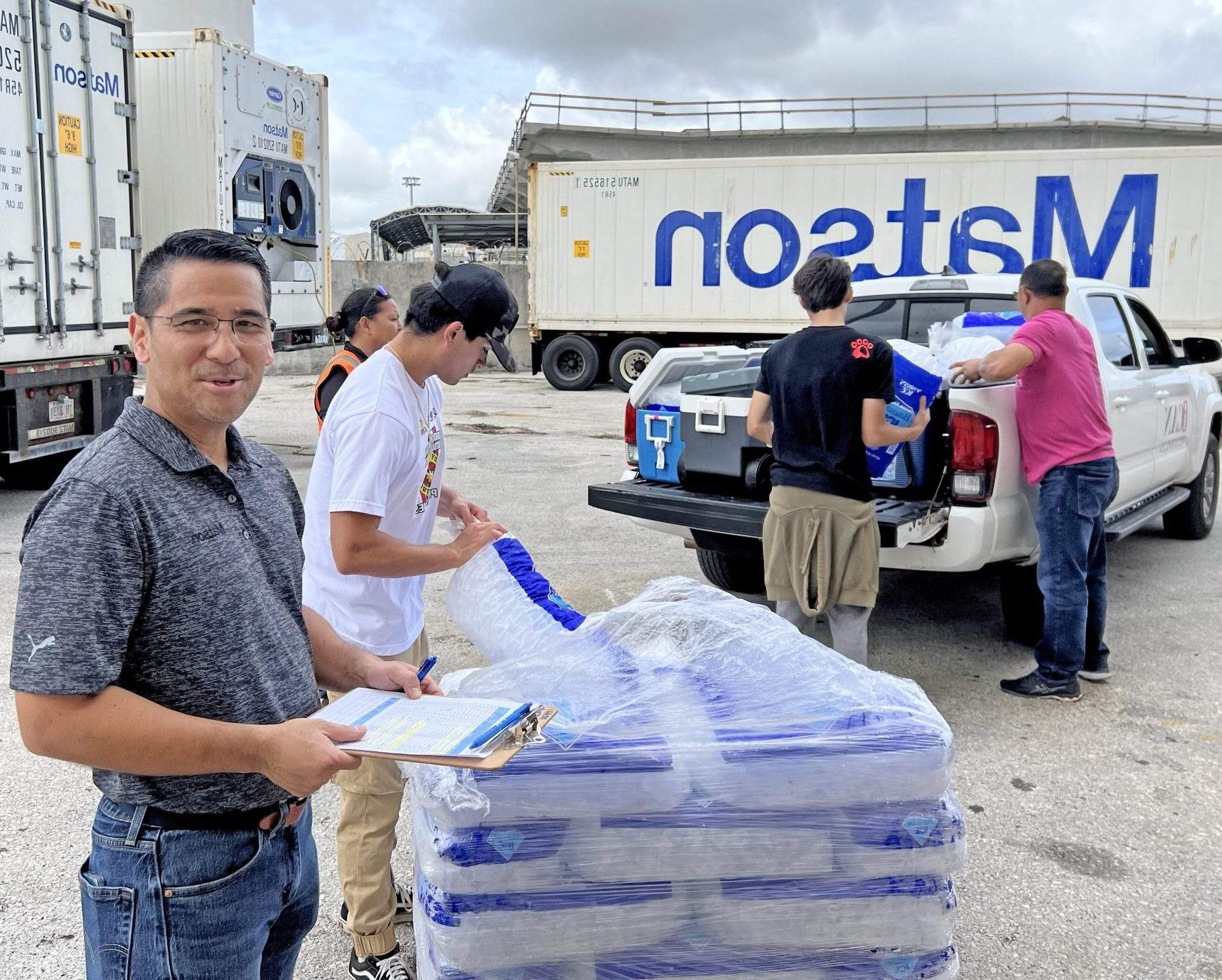 澳博体育app下载 employees move bags of ice from a pallet into ice chests with 澳博体育app下载 reefer and containers in the background.